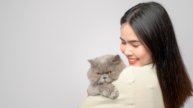 한 젊은 여성이 흰색 바탕에 스튜디오에서 고양이와 노는 사랑스러운 고양이를 안고 있다