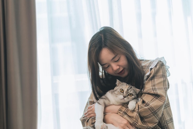 A young woman is holding lovely cat playing with cat