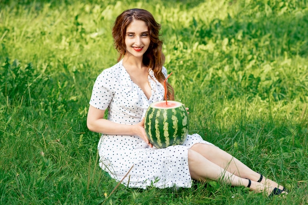 Young woman is holding watermelon on the grass outdoor