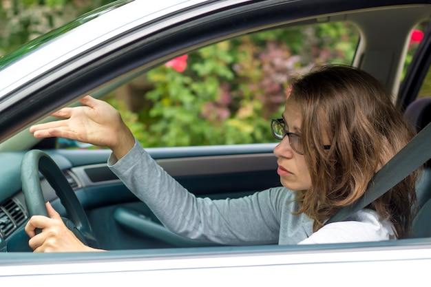 A young woman is indignant sitting in the car during a traffic jam. 