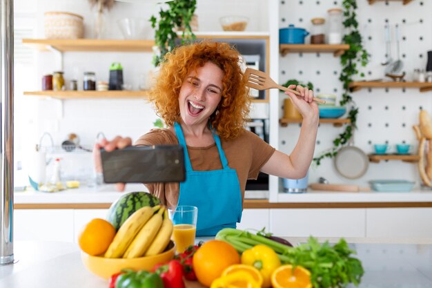 Photo young woman is in the kitchen she has wireless headphones on she is dancing and singing