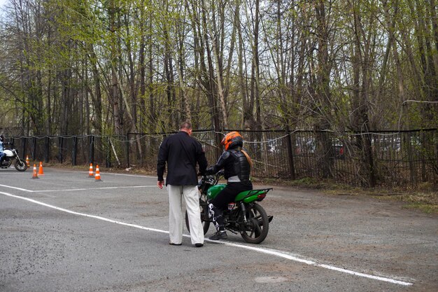 Foto una giovane donna sta imparando a guidare una moto in una scuola di motociclismo lei è insegnato da un insegnante