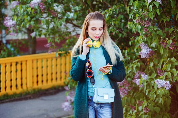 Young woman is looking at her phone choosing music to listen