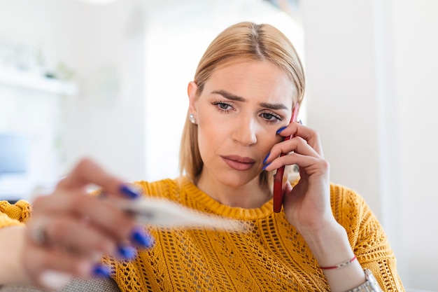 Photo young woman is looking at the thermometer she has fever calling her doctor beautiful woman with symptoms called covid19 emergency number to report her medical conditions