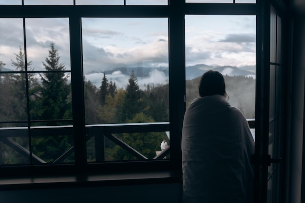 Young woman is looking through the window at the mountains