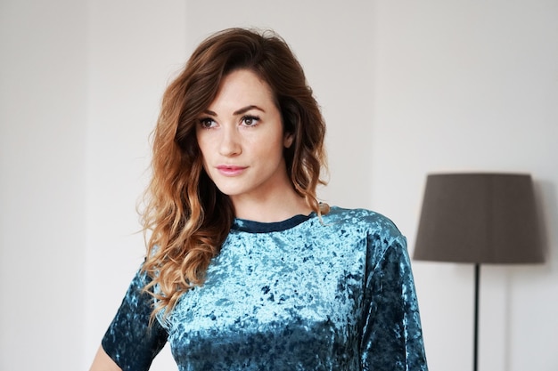 Young woman is lost in thought standing in living room with floor lamp