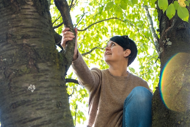 Young woman is lying on a branch of a tree in the forest