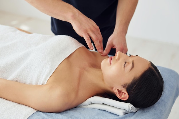 Young woman is lying down when man doing massage of her body at spa