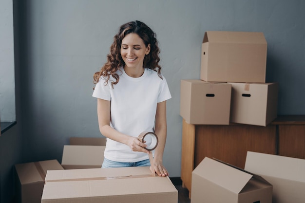 Young woman is packing cardboard containers with tape moving
service worker preparing boxes