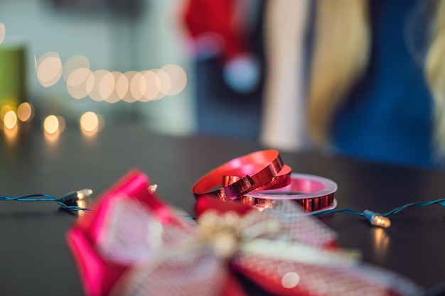 Young woman is packing presents present wrapped in craft paper with a red and gold ribbon for