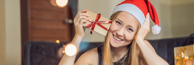 Young woman is packing presents present wrapped in craft paper with a red and gold ribbon for