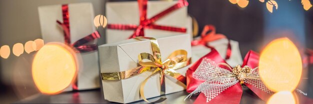 Young woman is packing presents present wrapped in craft paper with a red and gold ribbon for