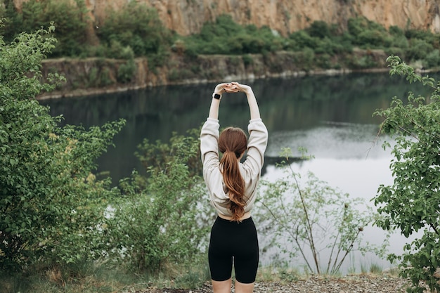 Young woman is practicing yoga at mountain lake