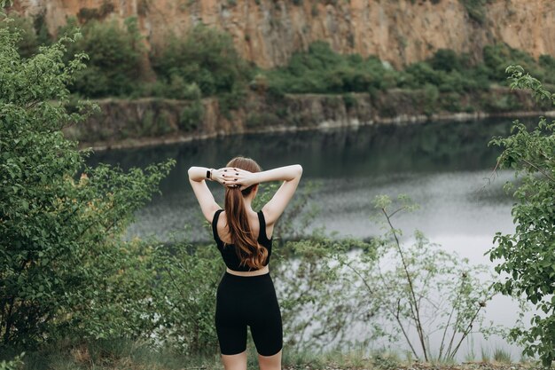 若い女性は山の湖でヨガを練習しています