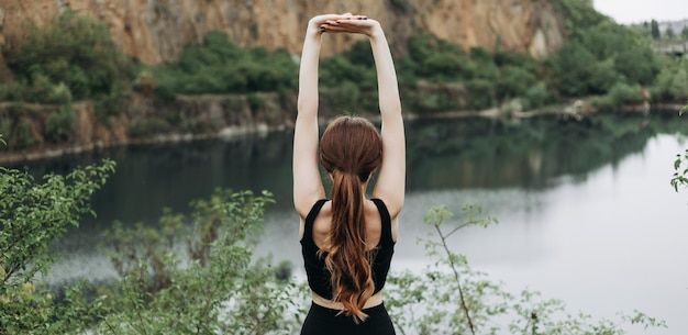 Young woman is practicing yoga at mountain lake