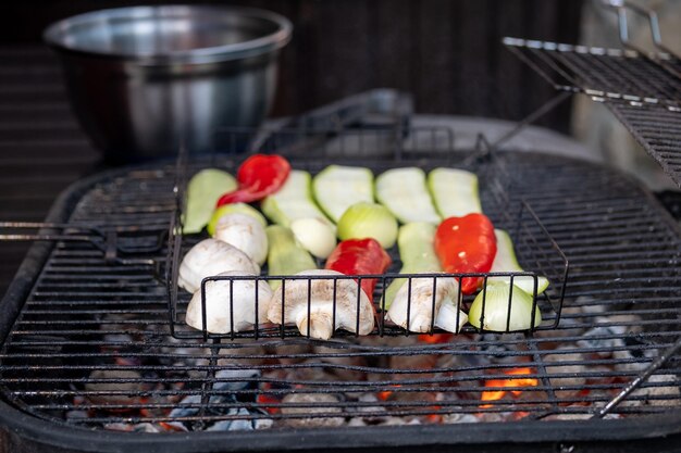 A young woman is preparing a barbecue Grilled vegetables sorted delicious grilled meat with vegetables on barbecue grill with smoke and flames in green grass