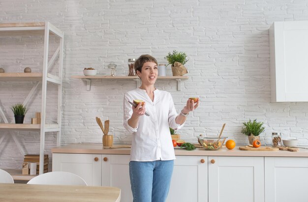 A young woman is preparing a vegetable salad in her kitchen Mixes vegetables in a large plate The concept of a healthy lifestyle