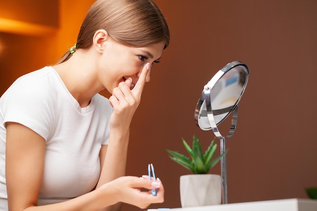 Una giovane donna indossa le lenti a contatto davanti allo specchio