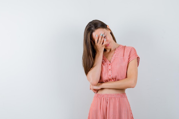 The young woman is putting her hand on face on white background