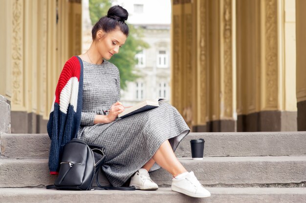 Young woman is reading book on the stairs