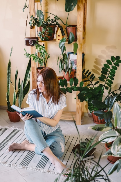 若い女性が自宅で検疫中に本を読んでいます。