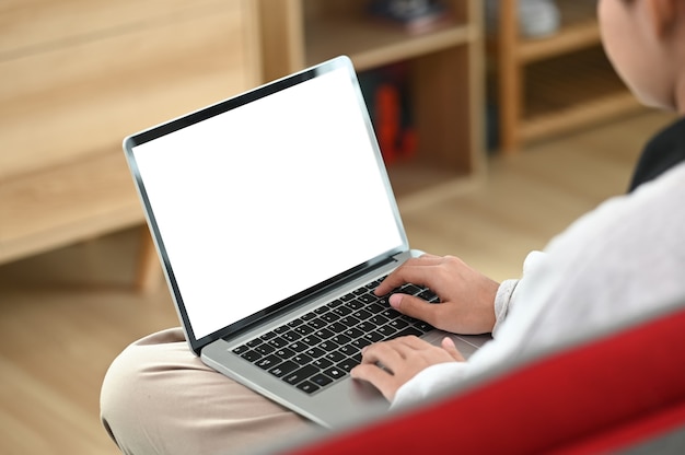 Una giovane donna si sta rilassando sul divano e utilizza il laptop a casa