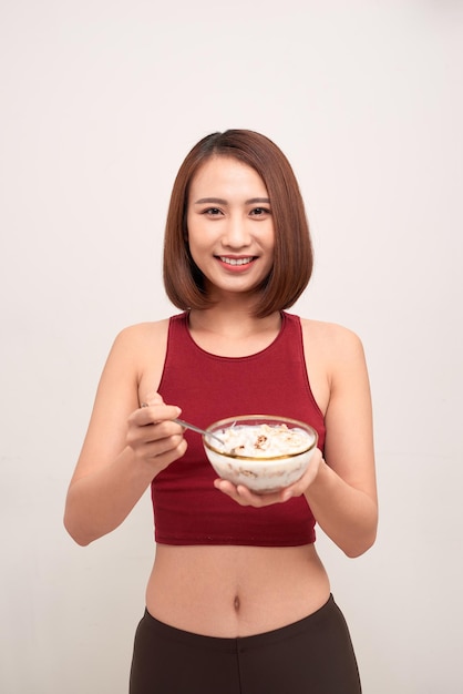 Young woman is resting and eating a healthy oatmeal after a workout.