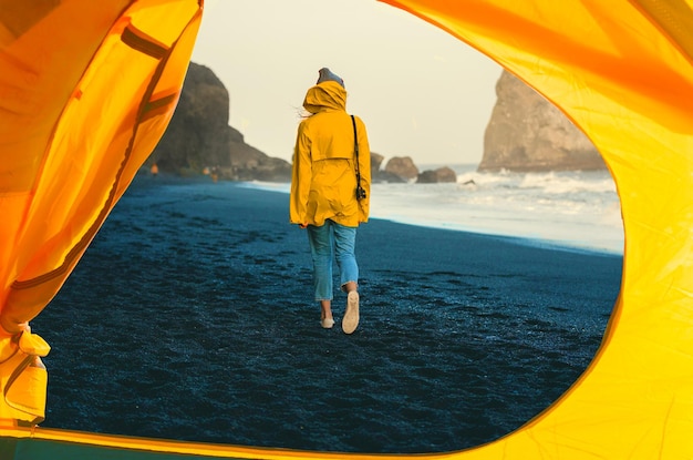 Young woman is setting up her tent in nature.