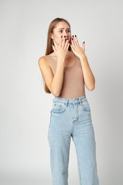 Young woman is in shock or surprise of the news against gray background