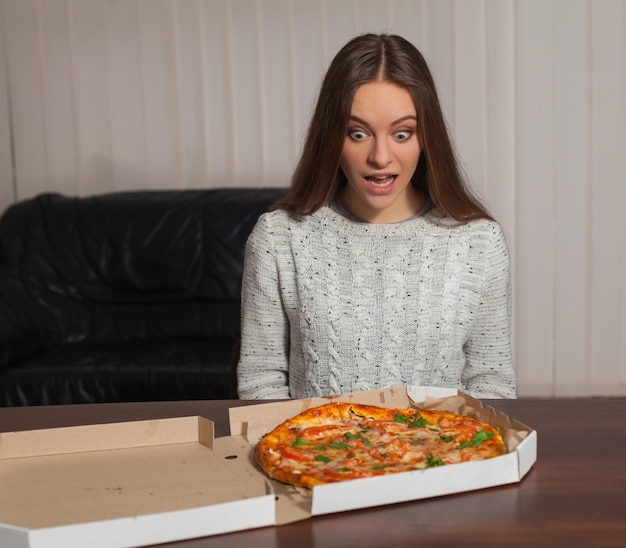 La giovane donna è seduta e sta andando a mangiare la pizza