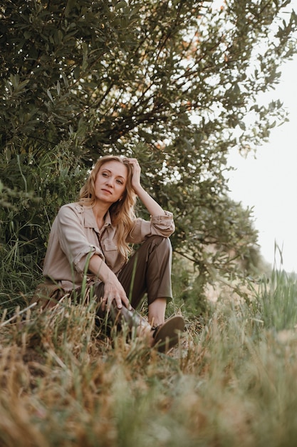 A young woman is sitting on the grass and looking into the distance