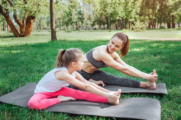 Young woman is sitting on mat with small girl