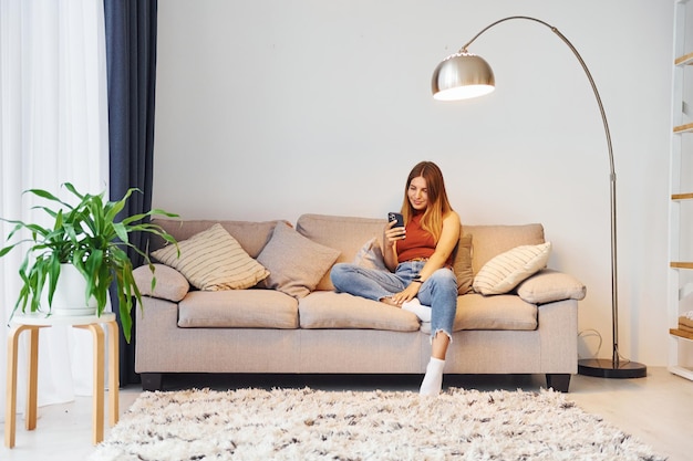 Young woman is sitting on the sofa in domestic room