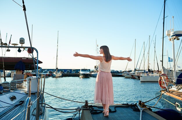 Young woman is standing back against the background of beautiful yachts