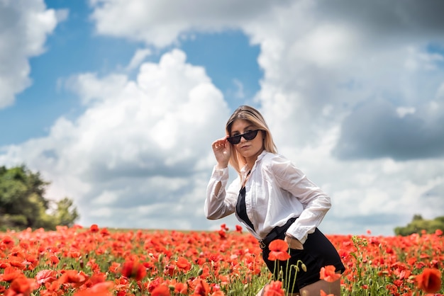 Young woman is standing near blooming poppy field . happy girl at outdoor, lifestyle