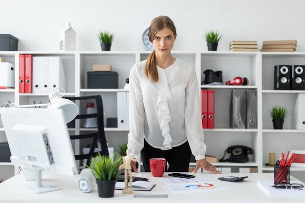 Photo a young woman is standing right next to a table in the office.