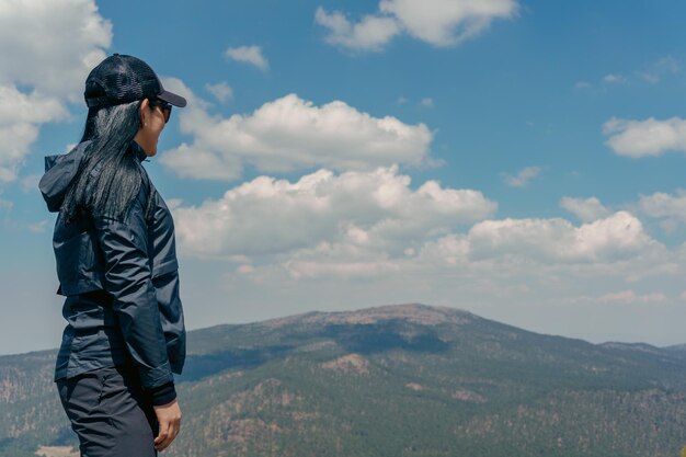 Photo a young woman is standing on top of a mountain