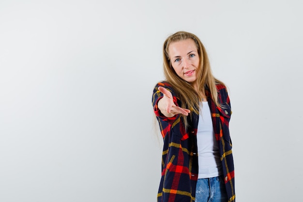 The young woman is stretching her hand to camera on white background