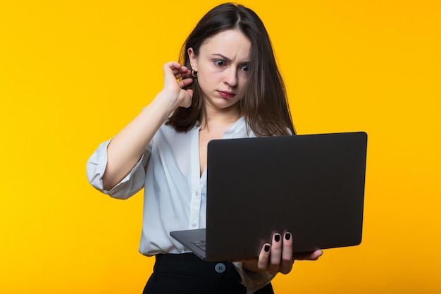 A young woman is surprised by what she sees in the laptop screen