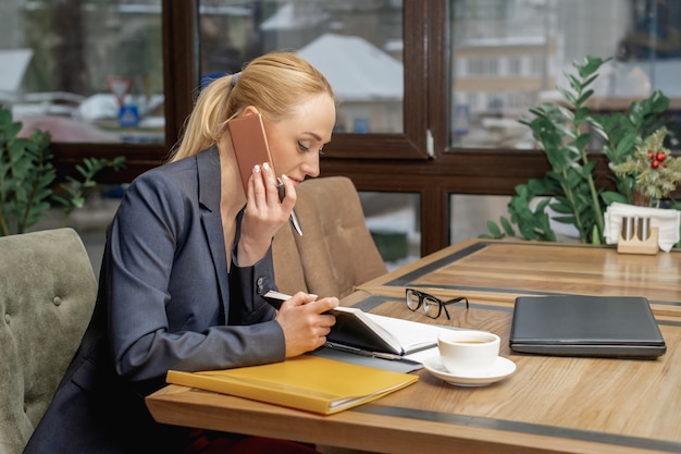 Young woman is talking by cell phone in office.