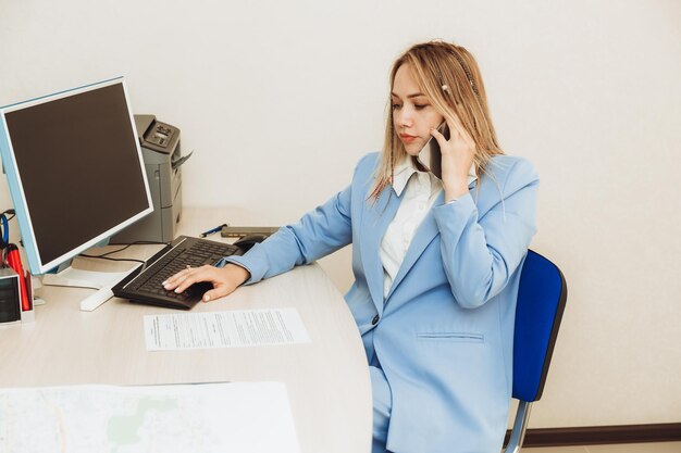 若い女性がオフィスで電話でクライアントと話しているビジネススーツを着た女性がオフィスで働いている