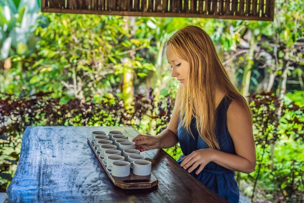 A young woman is tasting different kinds of coffee and tea, including coffee Luwak.