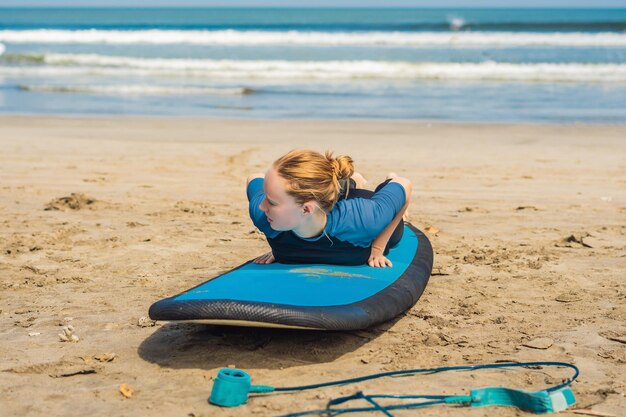 Young woman is training to stand on the surf before the first surfing lesson.