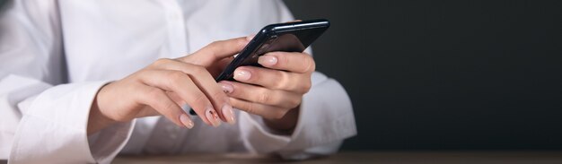 A young woman is using her smart phone at a table