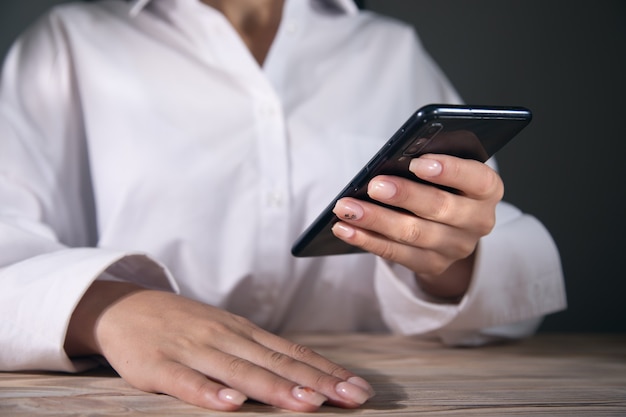 A young woman is using her smart phone at a table