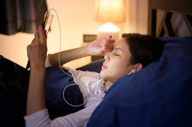 A young woman is using tablet , watching movies or video call to her friends or family in her bedroom , night Light	