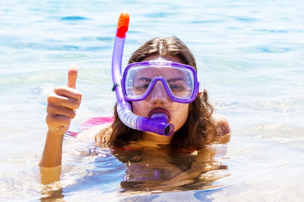 若い女性は海でダイビングマスクと水泳用チューブを着用していますシュノーケリング機器