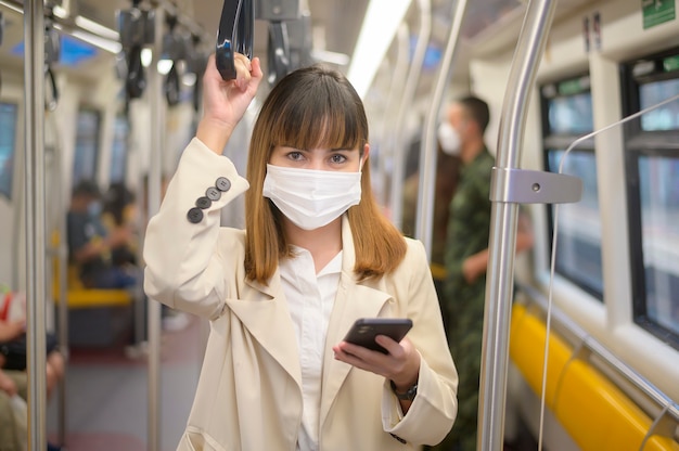 A young woman is wearing protective mask in metro , covid-19 protection , safety travel , new normal , social distancing , safety transportation , travel under pandemic concept