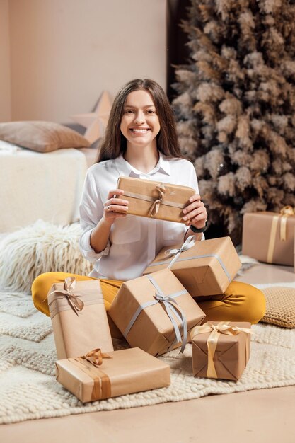 若い女性は休日のクリスマスプレゼントを包んでいます