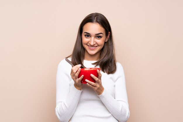 Young woman over isolated background holding a bowl of cereals